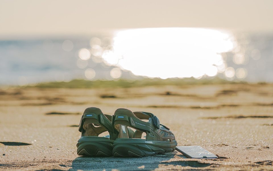 Smartphone og sandal på en strand