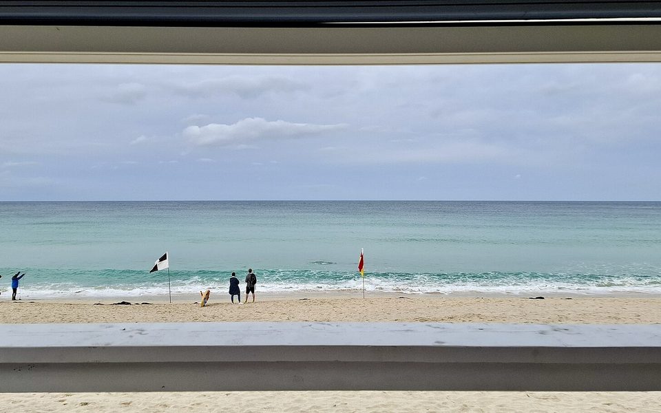 Sikkerhedsflag og badegæster på en strand med blæst